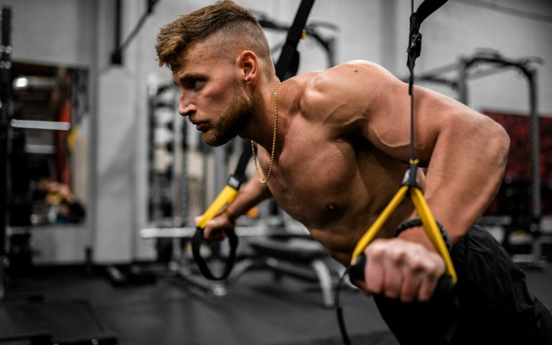 topless man in black pants holding black and yellow exercise equipment